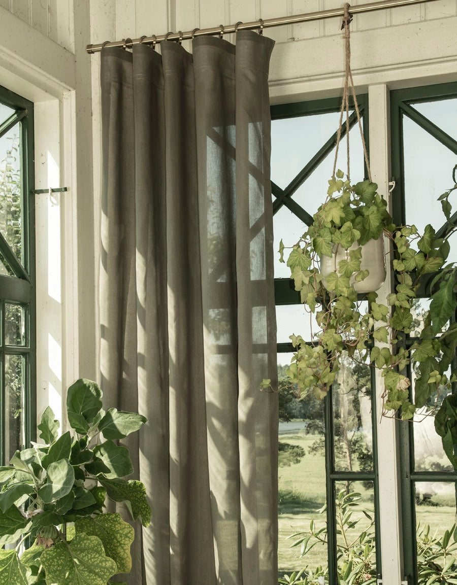 Gardinstång i antikmässing med grön gardin i uterum