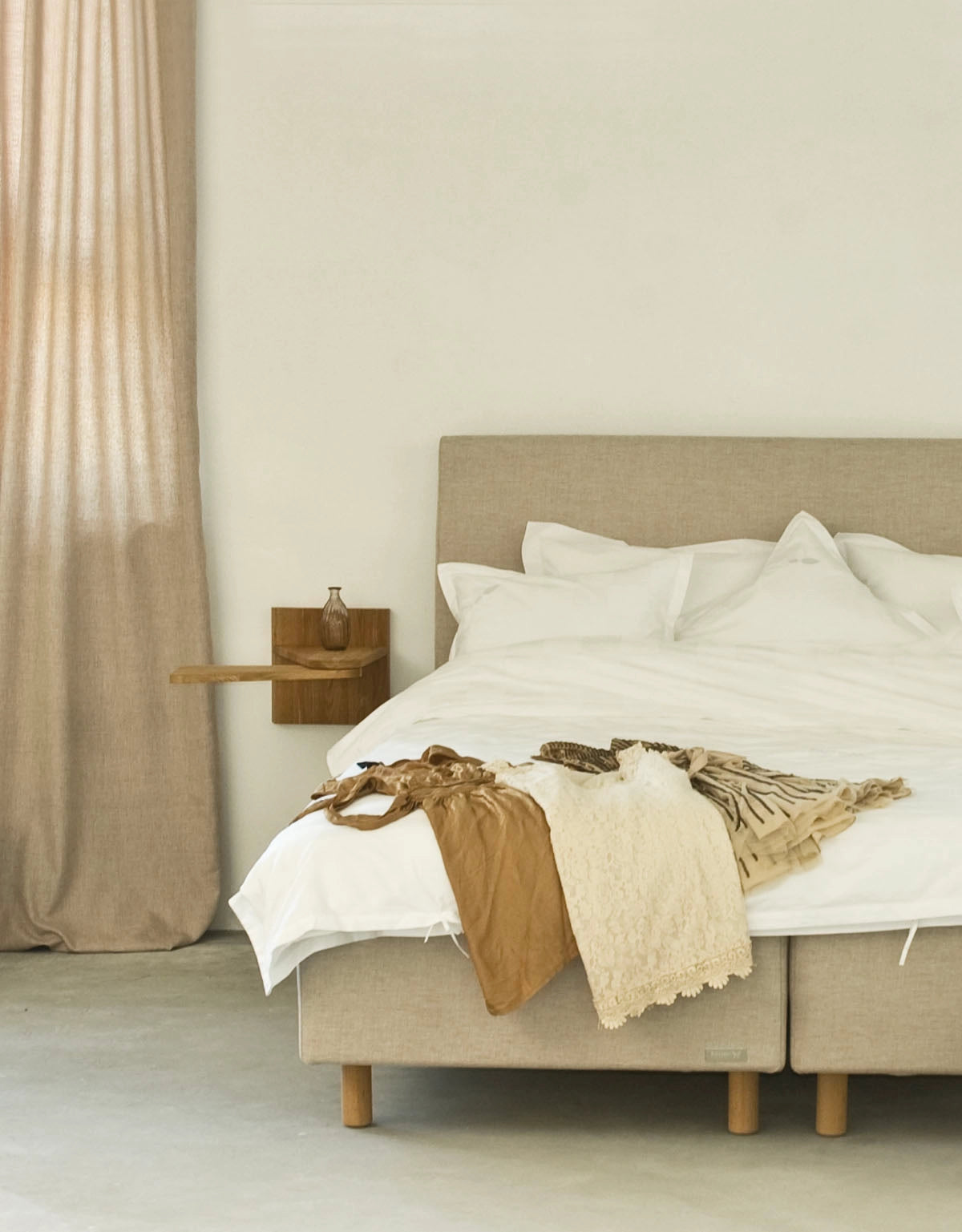 Sängben i trä på en beige säng i lantligt sovrum