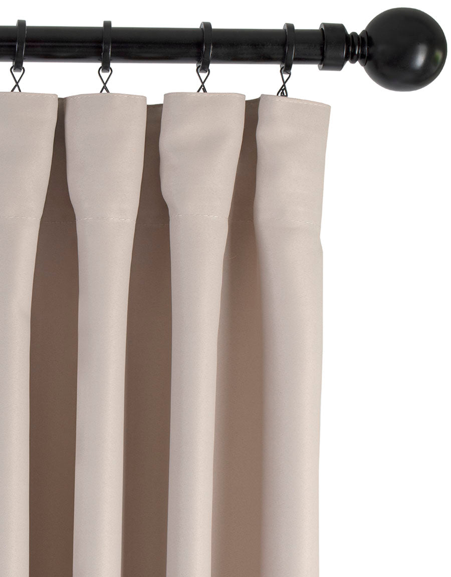 Beige gardin med fingerkrokar upphängd i ringar på stång