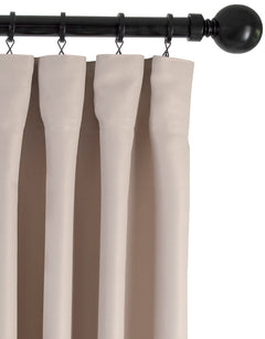 Beige gardin med fingerkrokar upphängd i ringar på stång