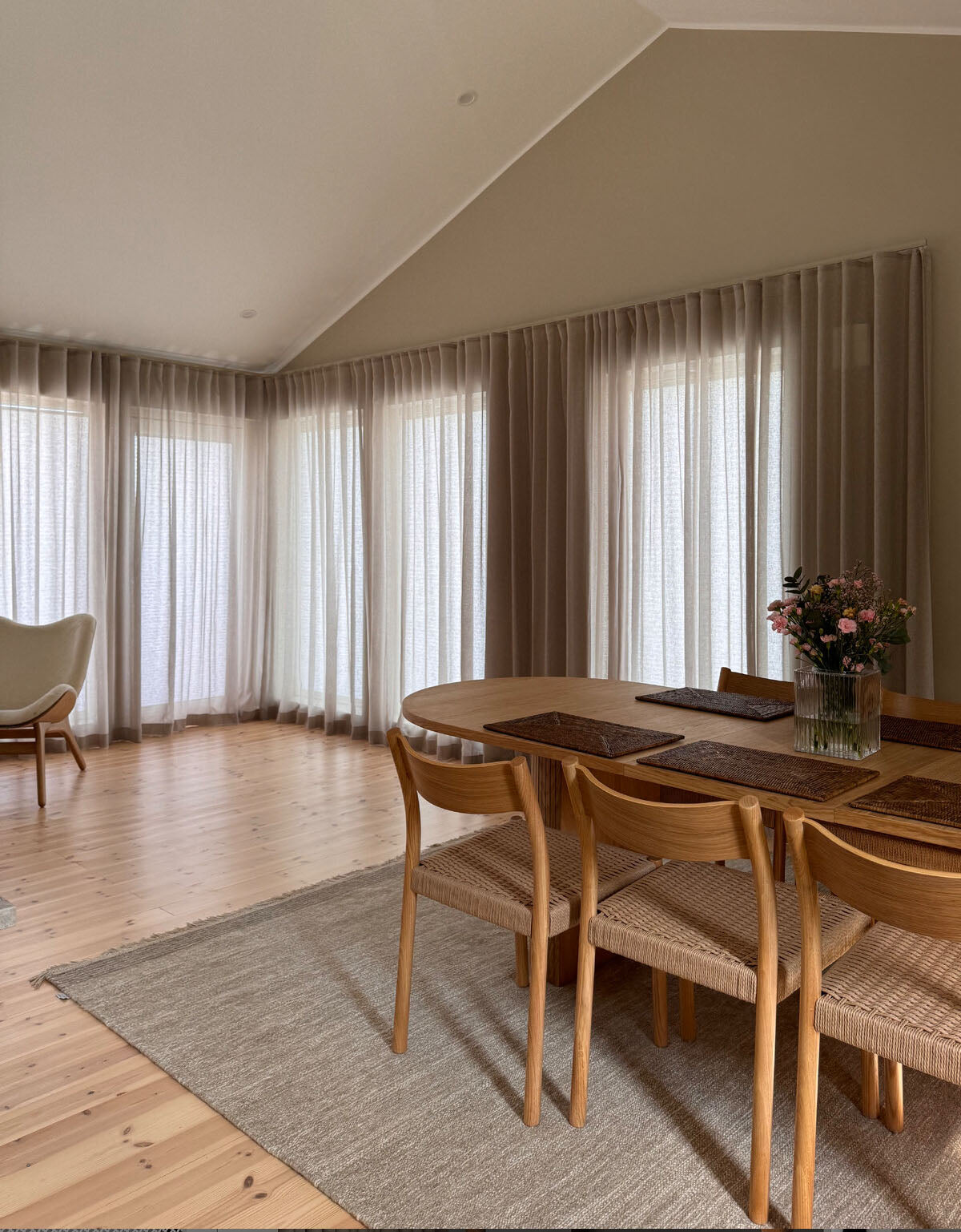 Beiga skira gardiner i stora fönster med beige gardinskena