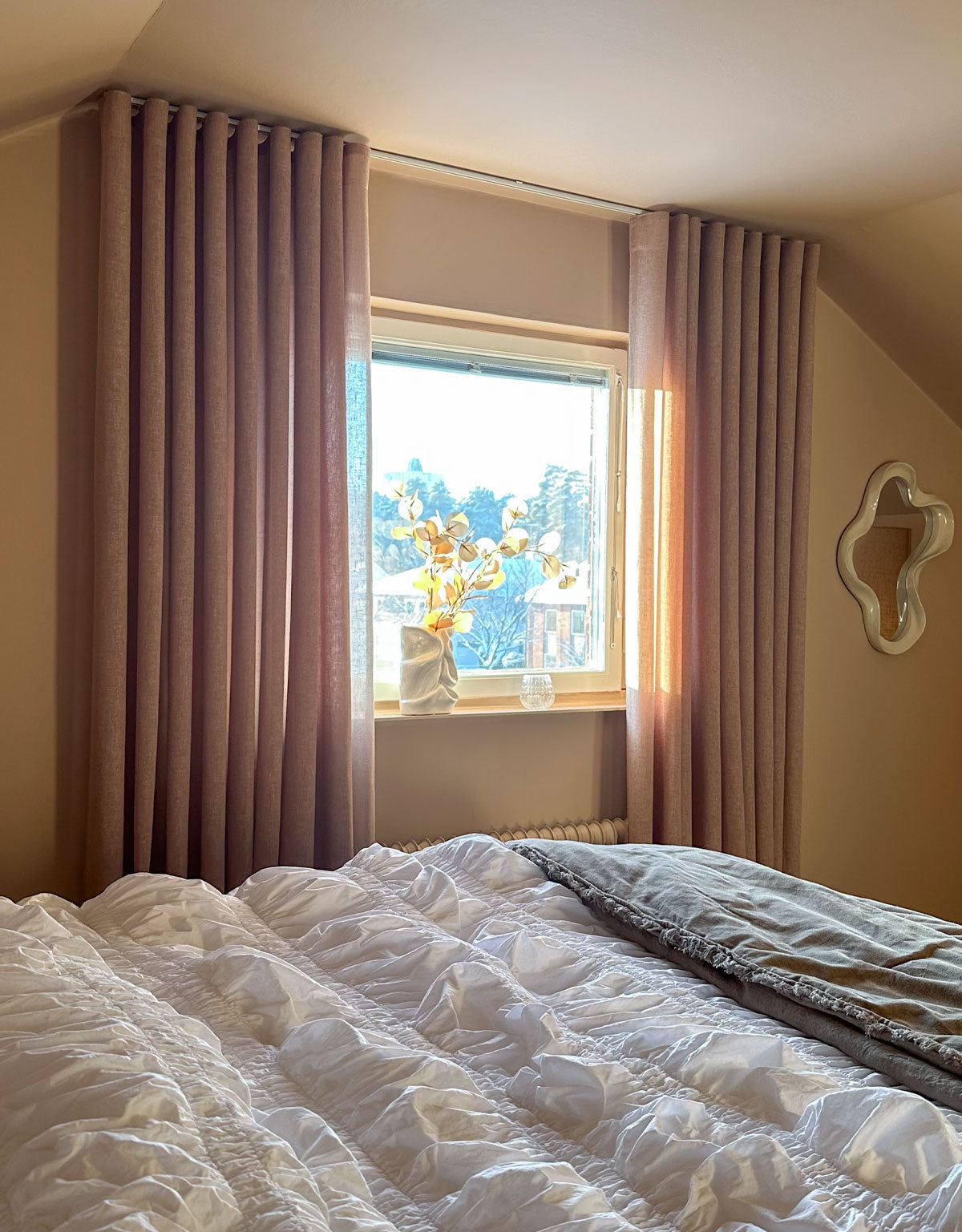 Beige gardin med hotellvågor på gardinskena