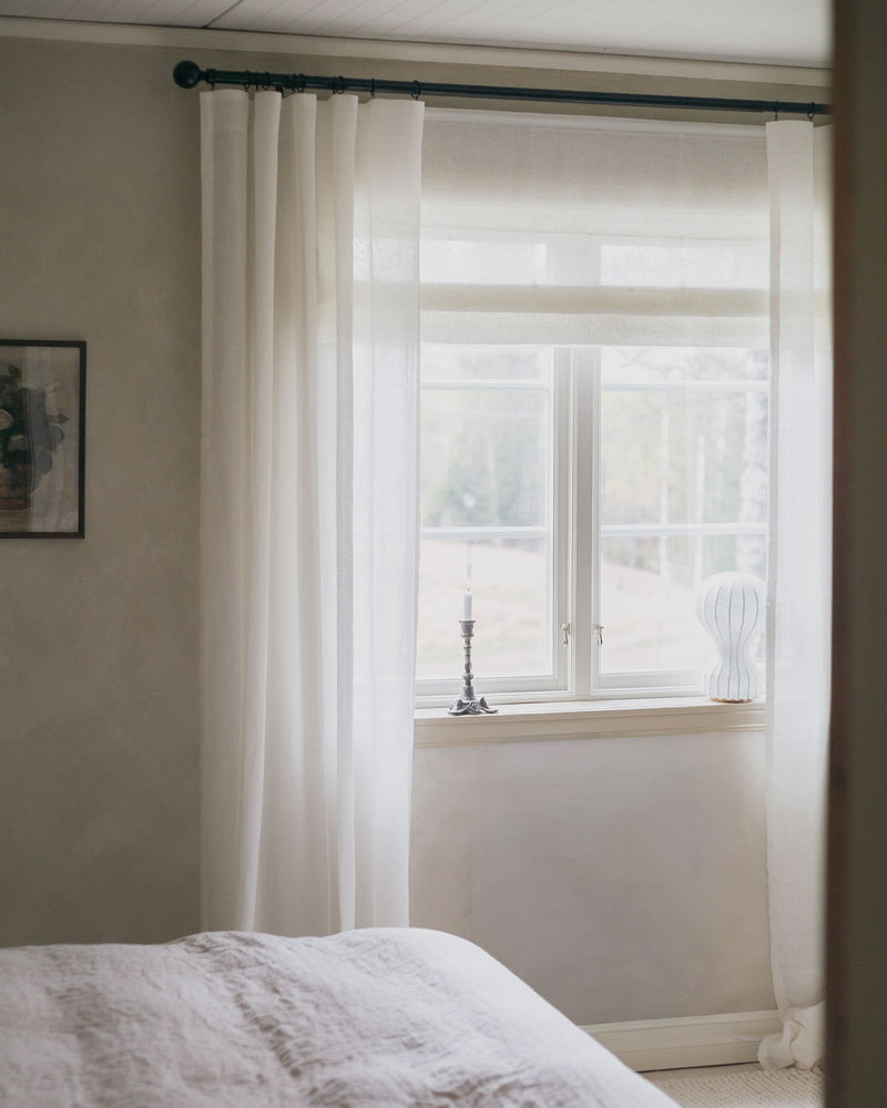 Vit hissgardin tillsammans med vita gardiner i linneblandning på svart gardinstång med rund knopp